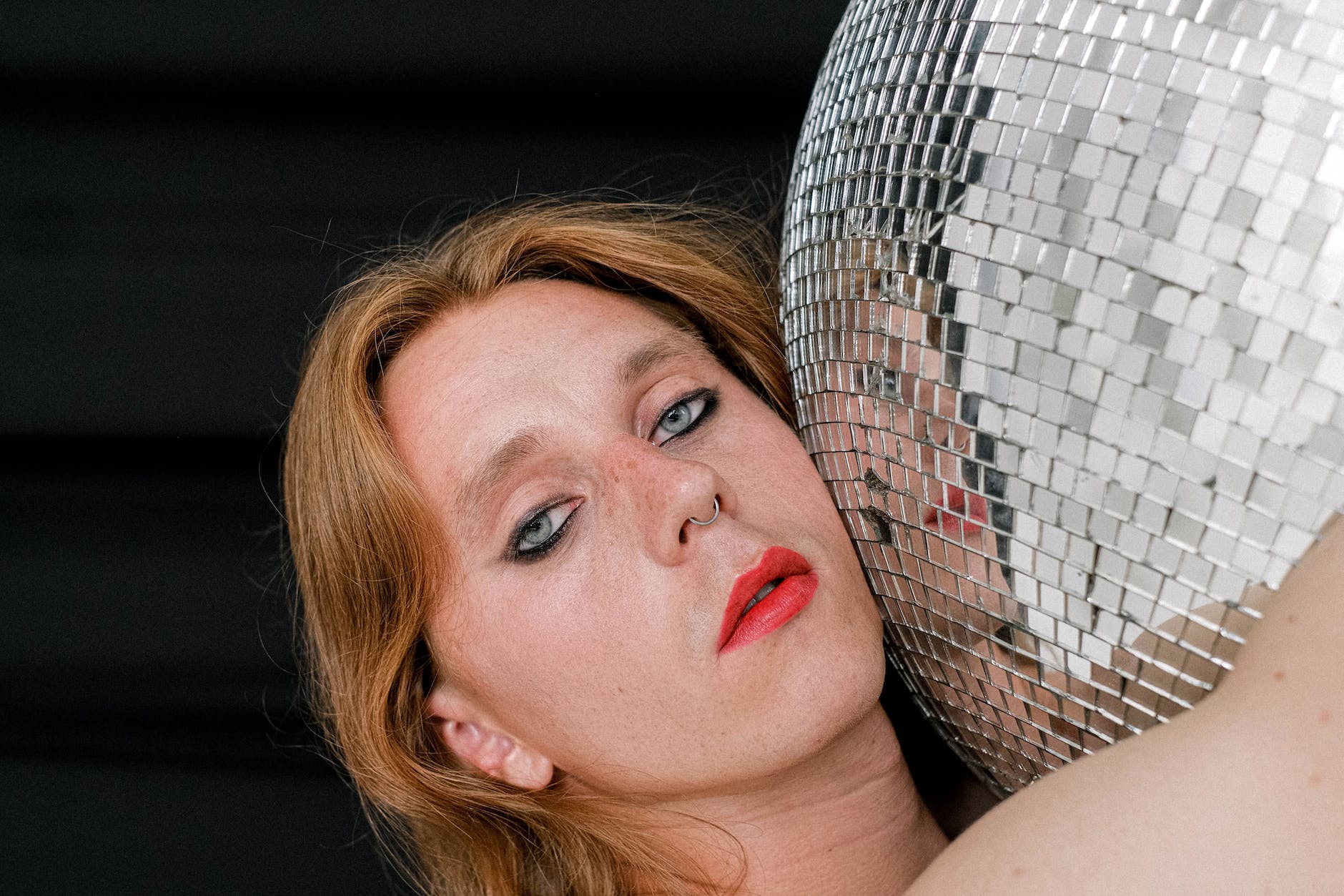 alluring young person with red lips hugging disco ball