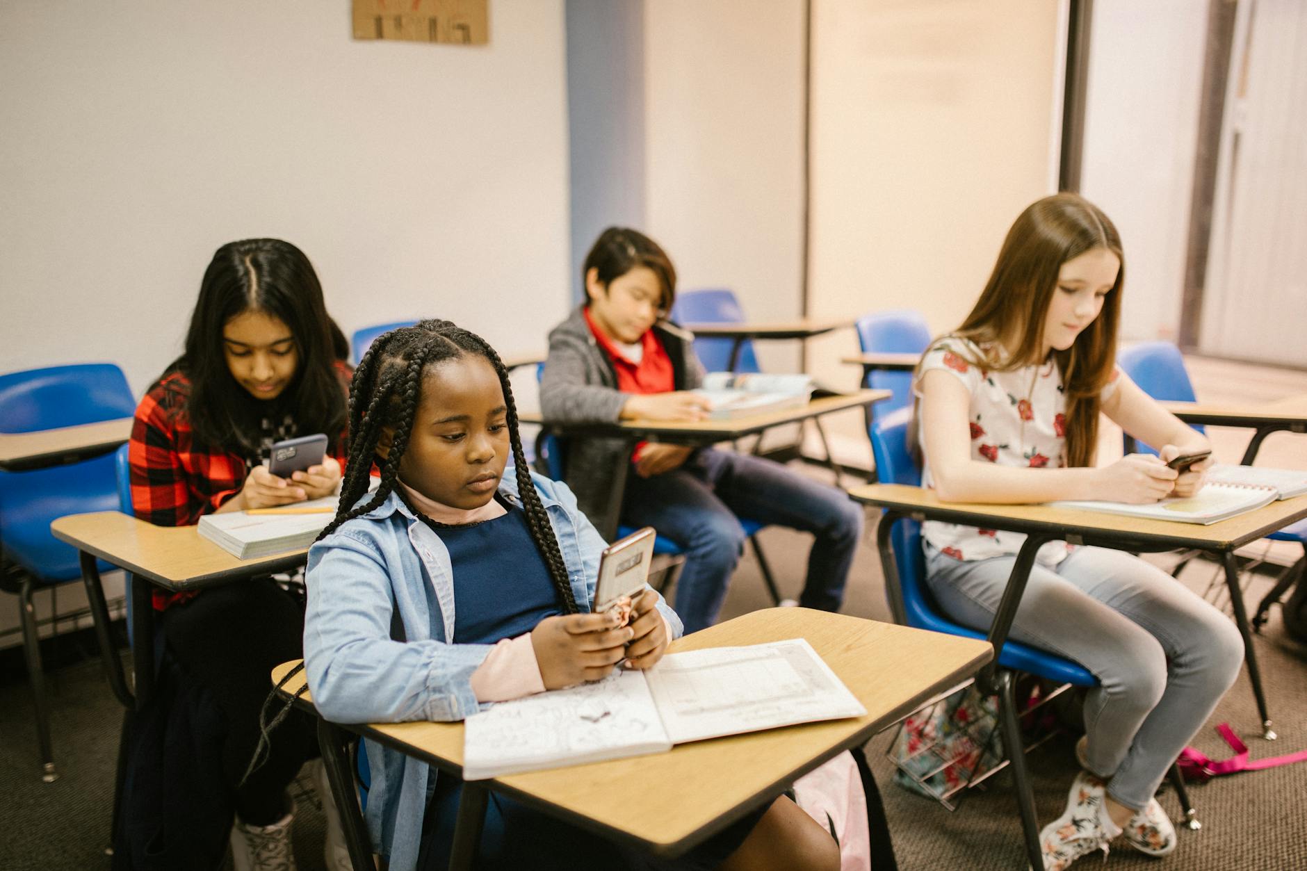 students sitting inside the classroom while using their smartphone