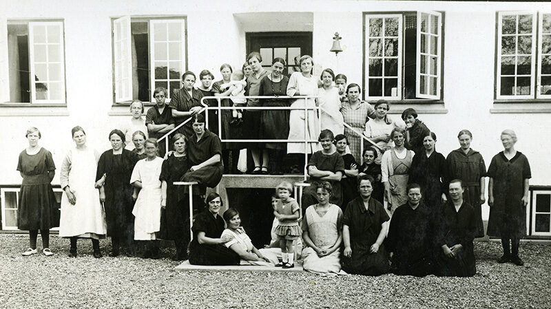 Mujeres danesas en la entrada del hogar de Sprogø en los años 30, símbolo de las esterilizaciones forzadas y abusos cometidos en Dinamarca durante el siglo XX.